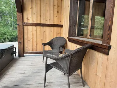 two wicker chairs sitting on the porch of a cabin at Explorer Creekside Cabin - Private Hot Tub in Golden