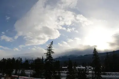 a cloudy sky with trees and mountains in the background at Golden Moments in Golden