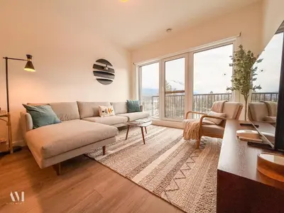 a living room with a couch and a large window at Oso Skyview Suite - DT modern 2 bed, 2 bath in Golden