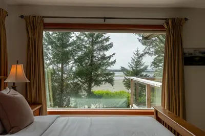 a bedroom with a large window looking out at the water at Chesterman on the Point - Beachfront in Tofino