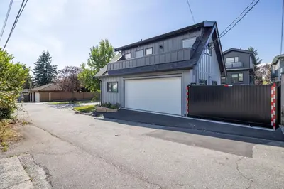 a house with two garage doors on a driveway at Sunny 1BR Detached Suite - Near City Center in Vancouver