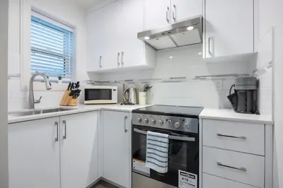 a white kitchen with a stove and a sink at Sunny 1BR Detached Suite - Near City Center in Vancouver