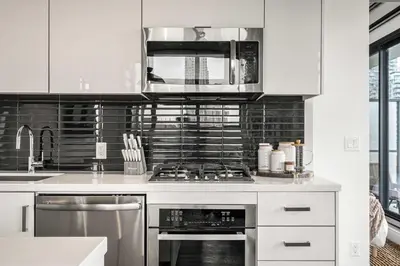 a kitchen with white cabinets and a stove top oven at The Domain Skyline View King Beds Pool Gym in Calgary