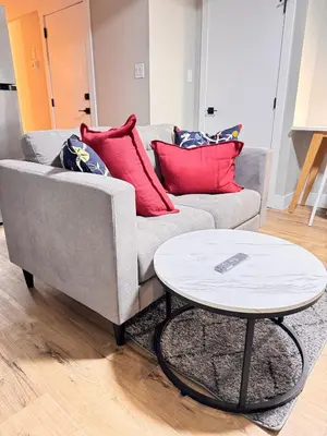 a grey couch with red pillows and a table at NorthEdge Suites in Edmonton