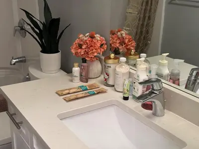 a bathroom sink with toiletries and flowers on it at Lovely 2 bedroom suite in Langford in Metchosin