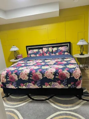 a bedroom with a bed with a floral bedspread at Roj exclusive comfort home in Edmonton