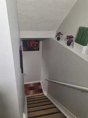 a staircase with white walls and wooden floors and a stair case at Roj exclusive comfort home in Edmonton