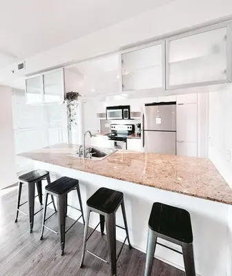 a kitchen with a large counter with four stools at Riverside Mint 2bd den 2 ba in Calgary