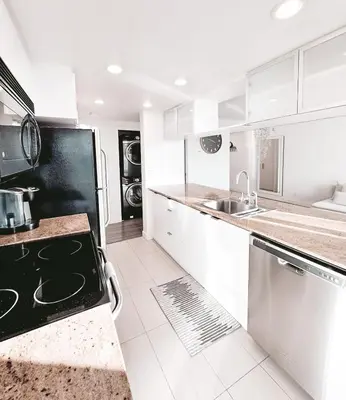 a white kitchen with a sink and a stove top oven at Riverside Mint 2bd den 2 ba in Calgary