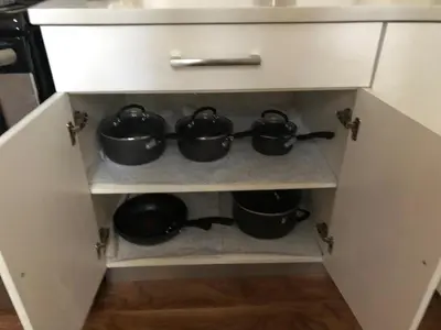 a kitchen cabinet with three pots on a shelf at 2 bed Suburban Oasis in Surrey in Surrey