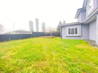 a yard with green grass next to a house at 5 Minutes away from Edmonds Station! Ideal location for all events & attractions in New Westminster