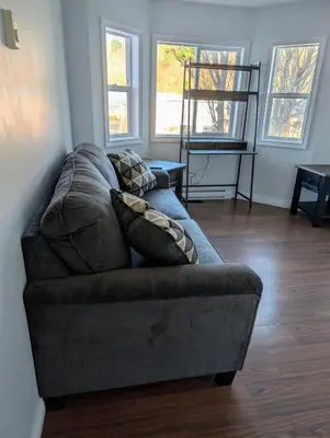 a couch in a living room with two windows at Executive Suite 2 Bedroom Serviced Apartment in Alert Bay