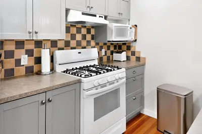 a kitchen with a white stove and a microwave at The Landing- Your Downtown Waterfront Oasis in Tofino