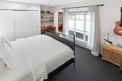 a bedroom with a bed and a large window at The Landing- Your Downtown Waterfront Oasis in Tofino