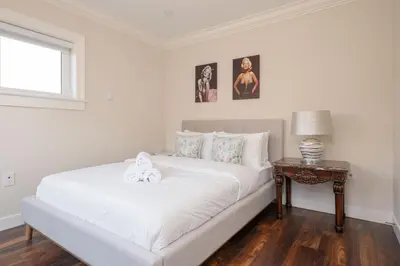 a bedroom with a white bed with a table and pictures at New Quiet Charming 1BR Suite near UBC & PW Park in Vancouver