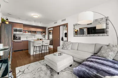 a living room with a couch and a kitchen at Modern Chic Apartment with Balcony & Workspace in Vancouver