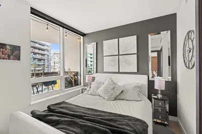 a bedroom with a bed and two windows at Modern Chic Apartment with Balcony & Workspace in Vancouver