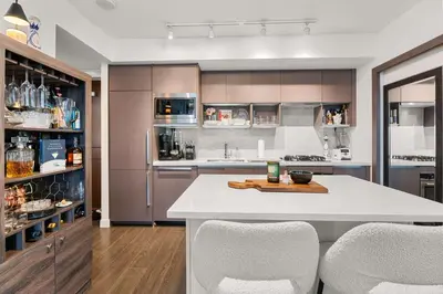 a kitchen with a white counter and some chairs at Modern Chic Apartment with Balcony & Workspace in Vancouver