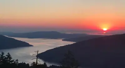 a sunset over a body of water with the sun setting at Blue Horizon Mountain Retreat B&B in Shawnigan Lake