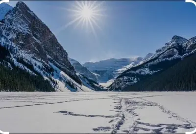 a snow covered mountain range with the sun in the sky at Luxury 2 Bedroom Mountain View Condo in Canmore
