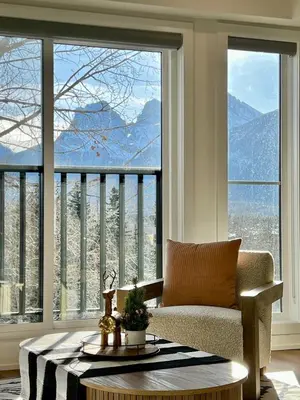 a living room with a couch and a large window at Luxury 2 Bedroom Mountain View Condo in Canmore
