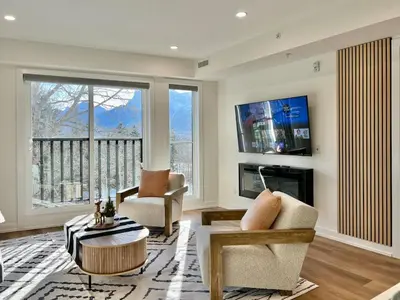 a living room with a large window and a tv at Luxury 2 Bedroom Mountain View Condo in Canmore