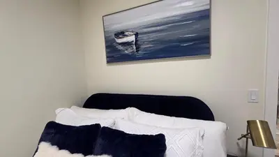 a bedroom with a bed and a painting of a boat at Home Away From Home With Free Netflix, Prime and Paramount in Calgary
