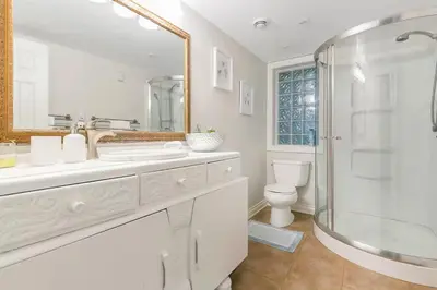 a white bathroom with a shower and a toilet at Spacious Oceanview Suite with Private Entrance in West Vancouver