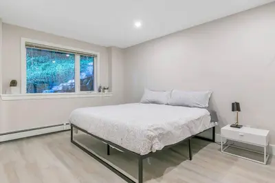 a white bedroom with a bed and a window at Spacious Oceanview Suite with Private Entrance in West Vancouver