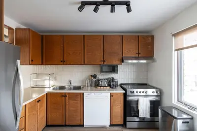 a kitchen with wooden cabinets and a white dishwasher at Unit 33 - 4 bedrooms - Sleeps 10 in Bélanger