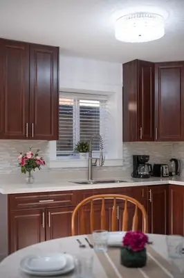 a kitchen with wooden cabinets and a sink and a table at Cozy 2B Suite in Great Location Near Trails & Shop in North Vancouver