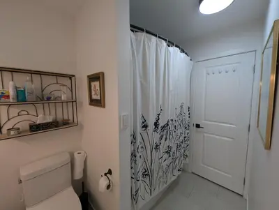 a white bathroom with a toilet and a shower at Colwood Hidden Home in Colwood
