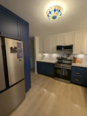 a kitchen with blue cabinets and a refrigerator at Colwood Hidden Home in Colwood