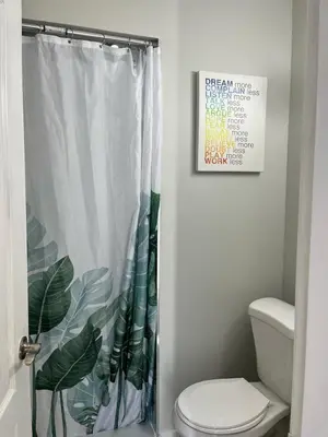a bathroom with a shower curtain with a toilet at Surrey Home - King George Blvd & Rapid Transit - Airport 25 Min - Free Parking & Wi-Fi in Surrey