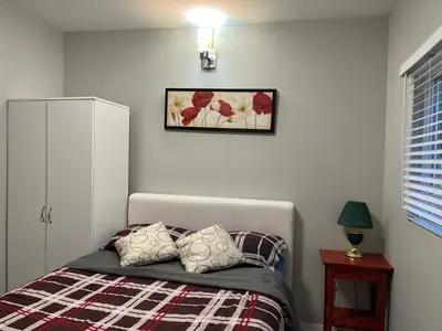a bedroom with a bed and a picture on the wall at Surrey Home - King George Blvd & Rapid Transit - Airport 25 Min - Free Parking & Wi-Fi in Surrey