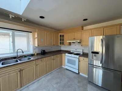 a kitchen with wooden cabinets and a stainless steel refrigerator at Vancouver Guest House - Airport & Downtown 15 Min - Free Parking & Fast Wi-Fi in Vancouver