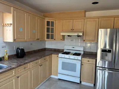 a kitchen with wooden cabinets and a white stove top oven at Vancouver Guest House - Airport & Downtown 15 Min - Free Parking & Fast Wi-Fi in Vancouver