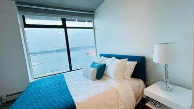 a bedroom with a bed with a large window at Ocean and Mountain View Home - Downtown Vancouver in Vancouver