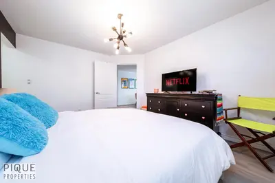a bedroom with a bed and a tv and a chair at The Neon Palace - King Bed - Fireplace - Netflix - UGPark in Edmonton
