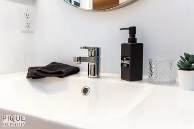 a bathroom sink with a soap dispenser on it at The Neon Palace - King Bed - Fireplace - Netflix - UGPark in Edmonton