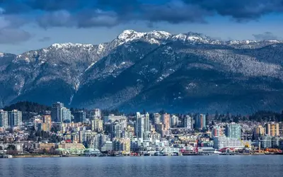 a city with snow capped mountains in the background at Central Lonsdale Gem in North Vancouver