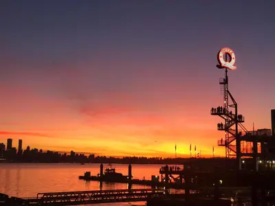 a sunset over a body of water with a sign at Central Lonsdale Gem in North Vancouver