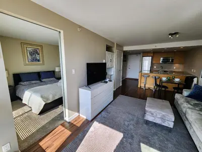 a bedroom with a bed and a living room with a television at Central Lonsdale Gem in North Vancouver