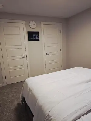 a bedroom with a bed and a clock on the wall at Livingston Calgary Lovely space in Calgary