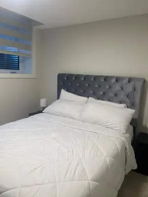 a bedroom with a white bed with a silver headboard at Livingston Calgary Lovely space in Calgary