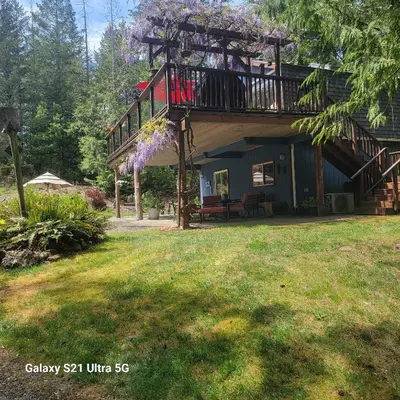 a house with a balcony with purple flowers on it at Beaver Hut Bed And Breakfast in Port Alberni