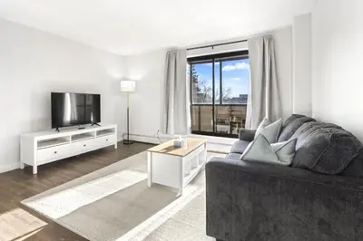a living room with a couch and a tv at Chic & Spacious 2BR at Stampede with Parking, AC in Calgary