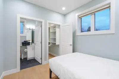 a white bedroom with a bed and two windows at 2393 Bonaccord Dr - Mattamel in Vancouver