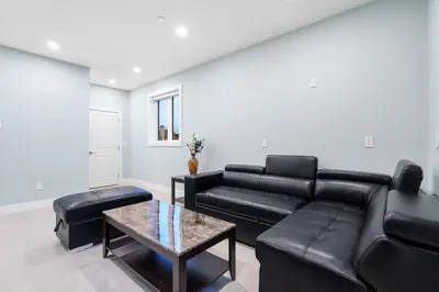 a living room with a black leather couch and a table at 2393 Bonaccord Dr - Mattamel in Vancouver
