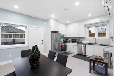 a kitchen with white cabinets and a black table at 2393 Bonaccord Dr - Mattamel in Vancouver